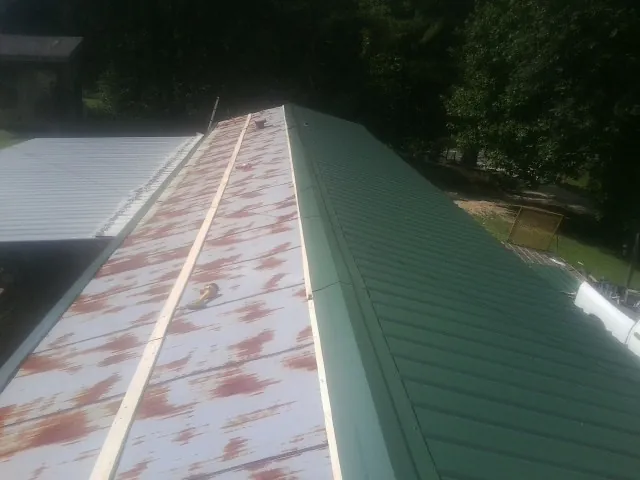 Old rusted panels beside newly installed green metal roofing — Wind Damage Roof Repair by Roofing Brothers in Dover